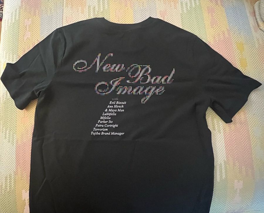 Black tee printed “New Bad Image” in chrome script, listing Evil Biscuit, Ann Hirsch, Maya Man, LuhFella, Mifella, Parker Ito, Petra Cortright, Terrorism and Tojiba Brand Manager